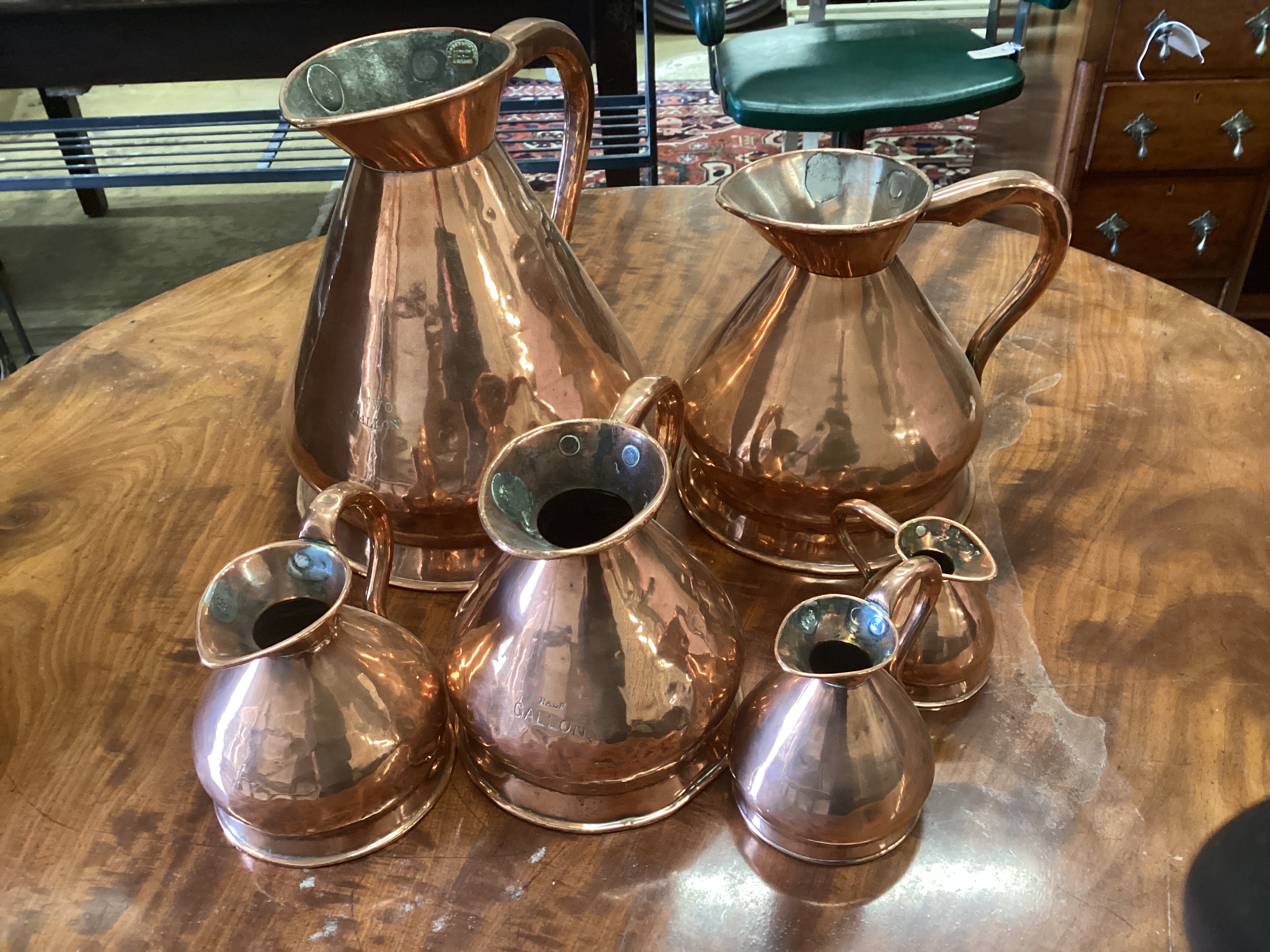 Six Victorian graduated copper flagon measures, one marked Farrow & Jackson, London, largest height 34cm